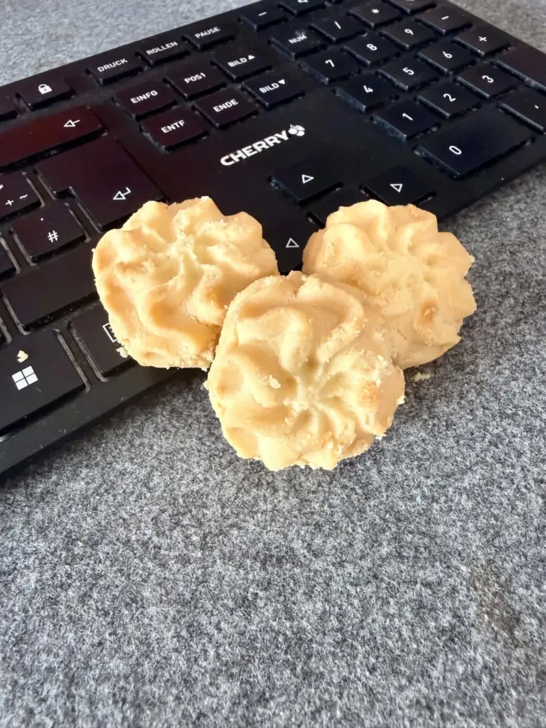 Drei Butterkekse auf einer Computertastatur als Symbolbild für Cookie-Banner, Cookies und Datenschutz auf Websites